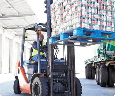 man operating a fork lift with products on lift inside of a warehouse